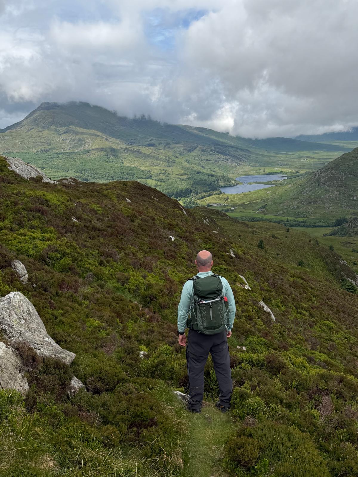 Mark Bailey mountain walking, overlooking a scenic valley and lake