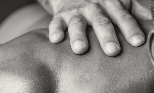 Sports massage therapist treating the shoulder of a muscular strength athlete