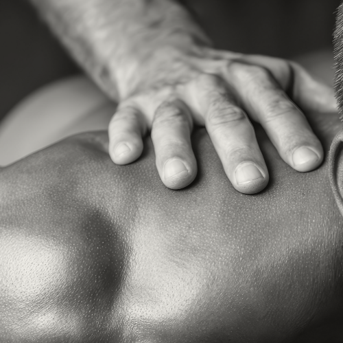 Sports massage therapist treating the shoulder of a muscular strength athlete